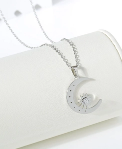 Detailed close-up of a silver crescent moon and sun star pendant with a sparkling zircon