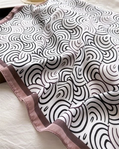 Detailaufnahme eines Satin-Seidenschals mit Wellenmuster und kontrastierenden Kanten