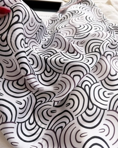 Detail eines weichen Seidenschals mit schwarz-weißem Wellenmuster und glattem Faltenwurf