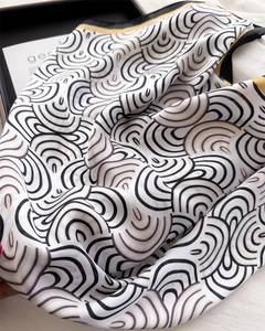 Detailansicht des Seidenschals mit geometrischem Wellenmuster und gelbem Rollsaumrand
