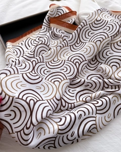 Nahaufnahme von geometrischem Wellenmuster auf braunem und beige Seidenschal