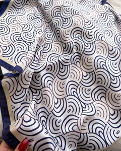 Detail eines Seidenschals mit marineblauem Wellenprint und beigem Kontrastrand