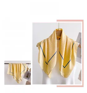 Detailed view of yellow silk scarf with white polka dots and navy blue border trim