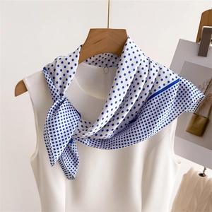 Close-up of elegant white polka dot silk scarf styled on a white sleeveless shirt