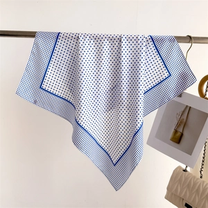 Detail of silk-like square scarf with elegant blue polka dots and border on a hanger