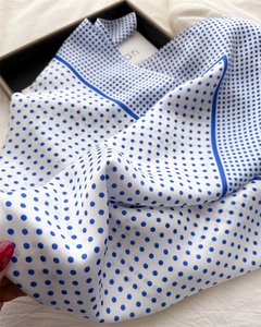 Detailed view of a blue polka dot satin square scarf folded in an elegant gift box