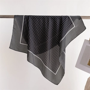 Detailed view of the black and white polka dot silk scarf with elegant white border