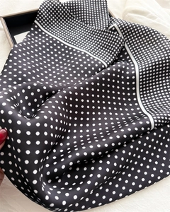 Detailed close-up of premium black and white polka dot silk scarf with elegant drape