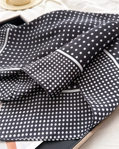 Close-up of black and white polka dot silk scarf with high-quality edge stitching details