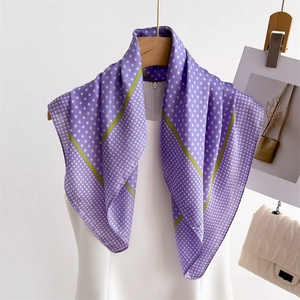 Detail of purple polka dot silk scarf with green stripes draped on a hanger