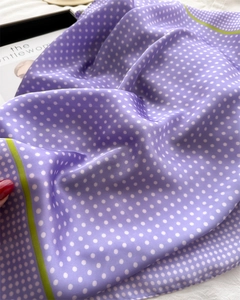 Detail of silk-like purple polka dot scarf with green stripes on a fashion magazine