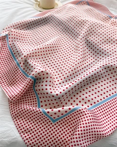 Close-up of red polka dot silk scarf on white fabric with a coffee cup detail
