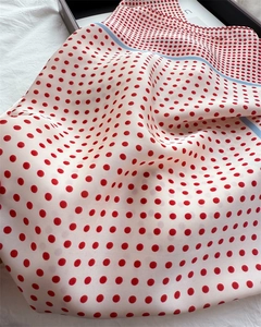 Close-up of silk-feel scarf with red polka dots and light blue striped border detail