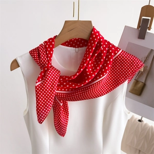 Close-up of a red silk-like scarf with white polka dots tied in an elegant bow