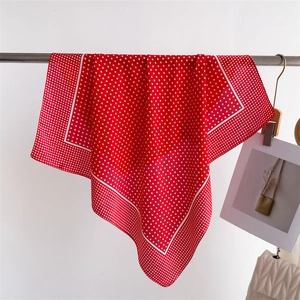 Detail of red silk-like square scarf with white polka dots hanging on a display