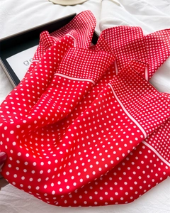 Detailed texture of red satin scarf with classic white polka dot patterns and soft draping
