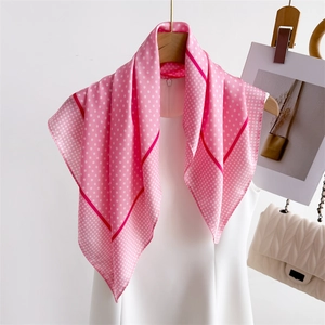 Close-up of pink polka dot silk scarf with red piping hanging on a white outfit
