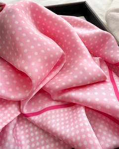 Close-up of pink silk scarf with white polka dots and elegant draped fabric texture