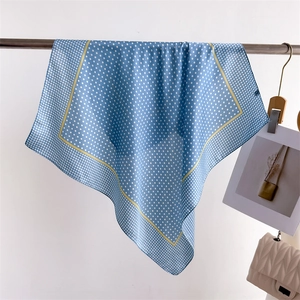 Detail of blue silk-like square scarf with white polka dots and yellow borders