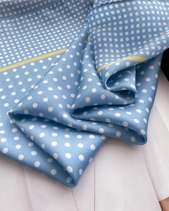 Detailed macro shot of light blue polka dot silk scarf with yellow edges and satin texture