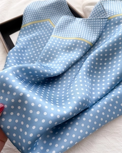 Detailed view of sky blue silk scarf with white polka dots and elegant satin texture