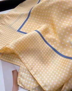 Detailed view of silk satin yellow scarf with white polka dots and blue border line