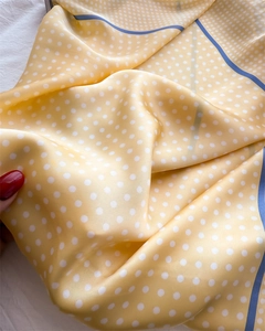 Close-up of yellow silk-like scarf with white polka dots and blue edge detailing