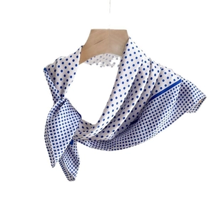 Elegant silk scarf with blue polka dots on white background hanging on wooden hanger