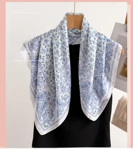 Detail of blue paisley and floral patterns on elegant white silk feel square scarf