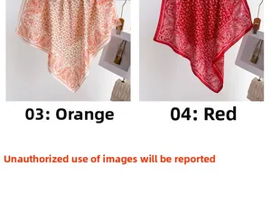 Detail of orange and red paisley silk square scarves hanging against a white wall