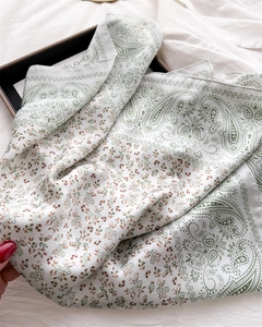 Close-up of paisley pattern on white faux silk scarf with fine stitching and satin luster
