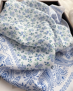 Close-up of elegant blue paisley pattern on ivory satin square scarf with silky texture