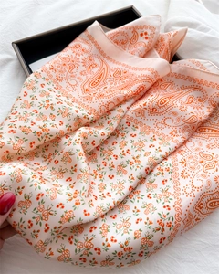 Detail of soft peach paisley silk scarf showing glossy texture and floral pattern
