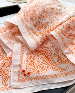 Close-up of paisley pattern silk-feel scarf showing satin texture and fine stitching