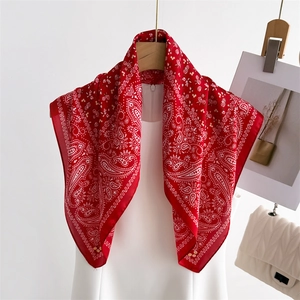 Elegant red paisley silk-like square scarf draped on a hanger with a white dress