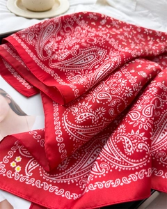 Close-up of red paisley silk-like square scarf styled with a magazine and coffee cup