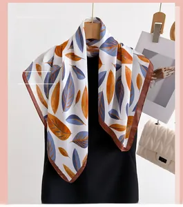 Detailed view of silk square scarf with orange and blue leaf print on wooden hanger