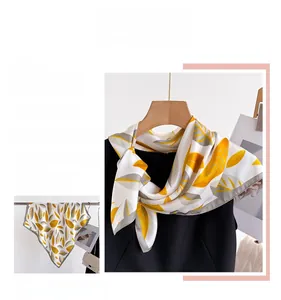 Detail shot of silk square scarf featuring yellow leaf print and dark gray border