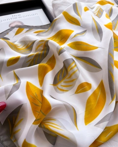 Detail of silk scarf showing yellow leaf pattern, elegant texture and rolled edges