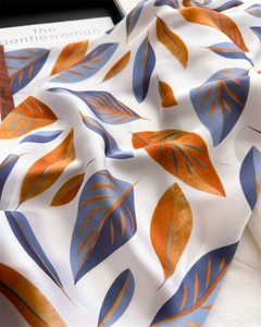 Detailed close-up of leaf print silk scarf with luxury fabric texture and rolled edges