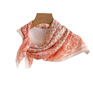 Elegant paisley print silk square scarf in beige and orange on a wooden hanger