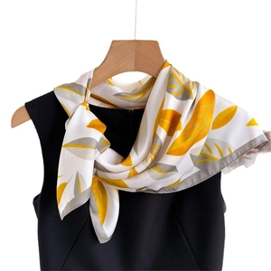 Elegant satin scarf with yellow and grey leaf print tied on a black dress neck
