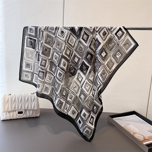 Detail of a black and white geometric silk scarf draped on a metal rack with modern pattern
