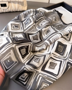 Detail of geometric pattern scarf with black and white square print on silk-like fabric