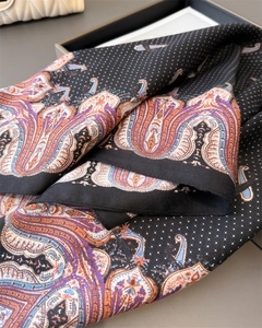 Close-up of black silk scarf featuring white polka dots and colorful paisley border patterns