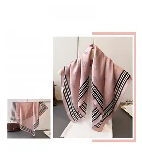 Detail of silk-like scarf featuring rose pink hue and black and white striped border