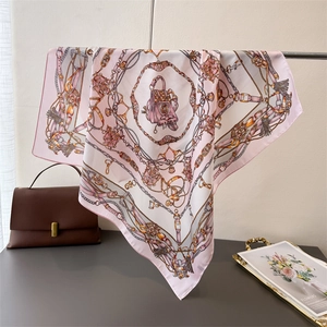 Pink satin square scarf with vintage chain and handbag print displayed on a metal rack