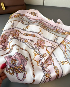 Detail of silk-like scarf with chain and buckle print featuring elegant satin texture