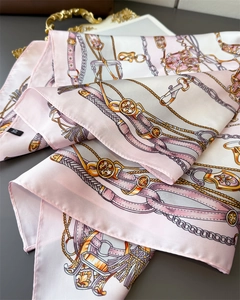 Detail of satin square scarf featuring elegant pink chain and bridle print patterns