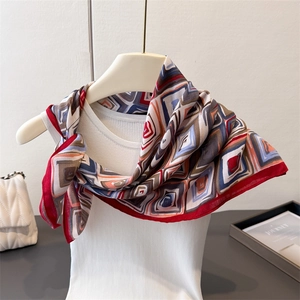 Detail of geometric pattern silk scarf layered on a white vest with a vintage chic vibe